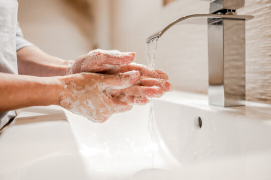 Girl washing hands with soap in bathroom