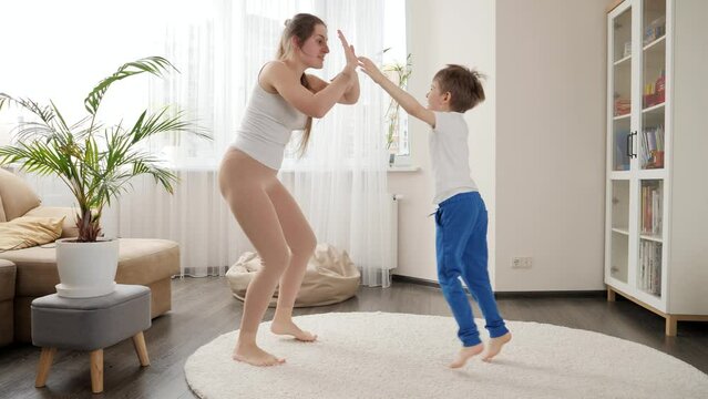 Cheerful mother and 6 year old son dancing at home together. Family having fun together, listening music, active lifestyle, parenting and child development.