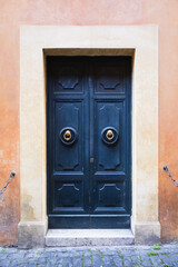 Elegant old blue double door entrance of building in Europe. Vintage wooden doorway of ancient stone house. Simple bright colored wood door with ring door handle. Architecture in Italy.