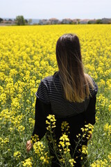 Back View of a Young Woman Standing on the Flower Field. Canola Field.