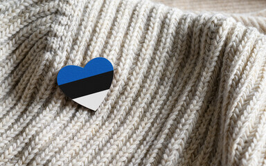 Flag of the Estonia in the shape of a heart on warm woolen things. copy space