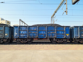 Fototapeta na wymiar Stock photo of blue color painted open goods wagon loaded with charcoal transported to power, metal, Chemical production.Picture captured under bright sunlight at Hyderabad, Telangana, India.