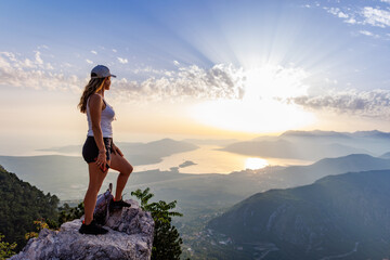 Happy girl with a backpack is on the edge of a high mountain in Montenegro