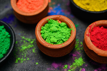 top view of colorful traditional holi powder in bowls isolated on dark background.Space for text . happy holi.Concept Indian color festival called Holi