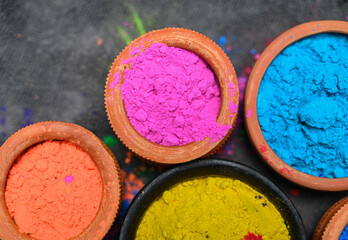 top view of colorful traditional holi powder in bowls isolated on dark background.Space for text . happy holi.Concept Indian color festival called Holi