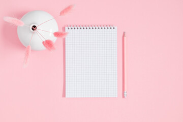Empty notepad mockup, dry flowers, fluffy rabbit tail flower on pink background. Spiral open...