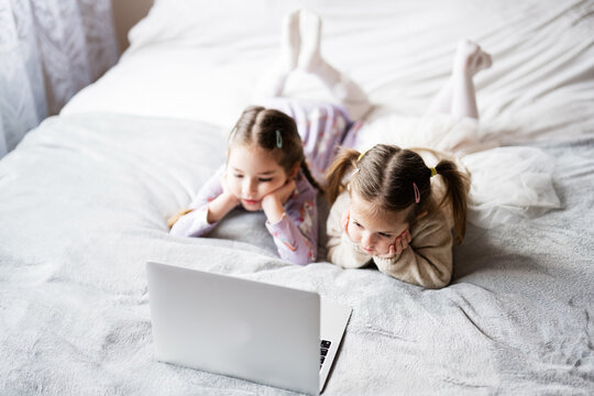 Two girls sisters watching on laptop. Technology and home concept.