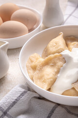 Fresh boiled dumplings in a light plate on a light background. Pattern, background. Homemade craft production, national traditions, Ukrainian cuisine. Close-up, background