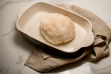 close-up top view of raw dough in a ceramic baking dish on the table