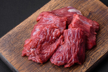 Raw beef cut into several pieces on a wooden cutting board