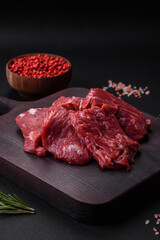 Raw beef cut into several pieces on a wooden cutting board