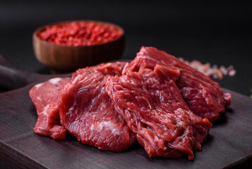 Raw beef cut into several pieces on a wooden cutting board