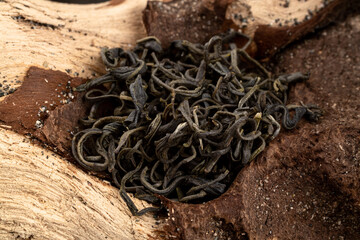 Close up Chinese green leaf tea. Dried tea leaves on wood background, top view. Macro