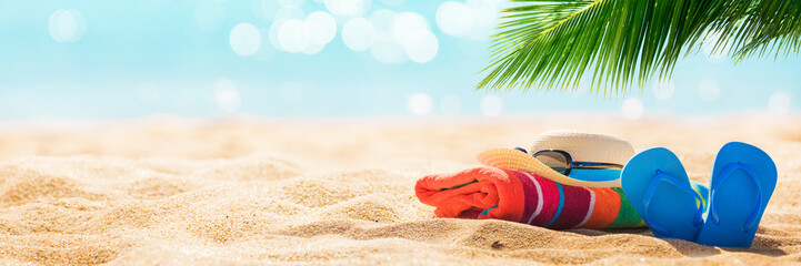 Summer holiday background with flip flops and palm tree on sandy beach