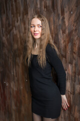 Fototapeta premium A sexy woman in a black mini-dress poses in the studio.