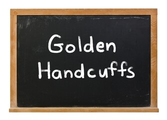 Golden handcuffs written in white chalk on a black chalkboard isolated on white