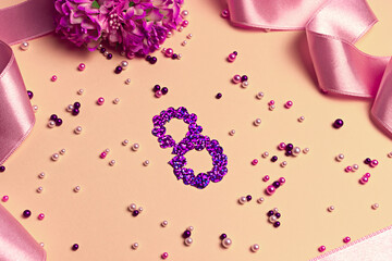 8th of March celebration. Greeting postcard with number 8 lined with purple glitter hearts on the peach colored background with flowers and ribbon above.