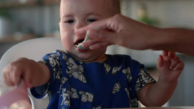 1 year old in high chair is fussy about eating - close up on face as she pushes spoon away - close up on face