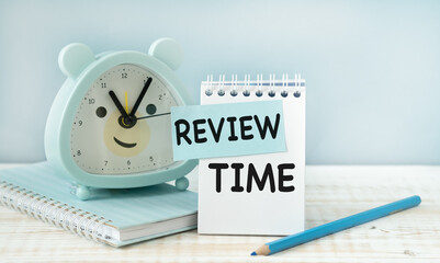 Review Time word on notebook with clock and blue pencil . Review and assessment concept.