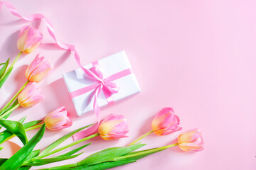 spring card, tulips and gift with pink ribbon on pink background, women's day, mother's day. High quality photo