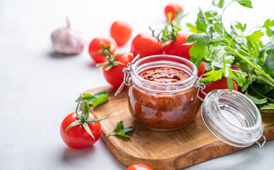 Obraz na płótnie Canvas Salsa sauce is a traditional Mexican sauce with tomatoes and hot peppers on a light background with fresh herbs close up.