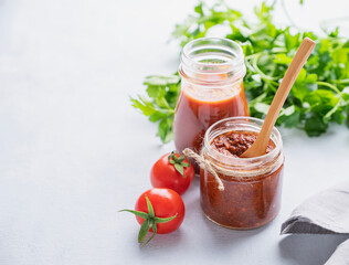 Salsa sauce is a traditional Mexican sauce with tomatoes and hot peppers on a light background with  fresh herbs.