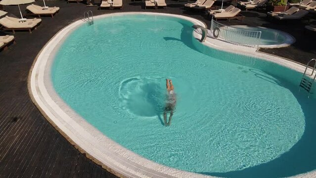 Woman in red bicini swimming in pool. Aerial view. Drone footage