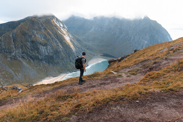 Man with backpack looking into the distance while hiking on a trail in Norway