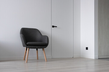 Gray chair against an empty white wall, with a concealed door