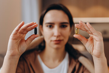 A woman holds pills in both hands in front of her face. Choice of drugs