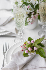 Beautiful table decor for a wedding dinner with a spring blooming apple tree flowers. Celebration of a special event. Fancy white plates, wineglasses