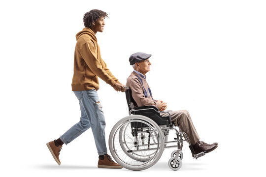 Full Length Profile Shot Of An African American Young Man Pushing A Senior In A Wheelchair