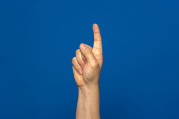 Curious man hand with index finger up isolated on blue background, he has had a great idea and wants to explain it to everyone