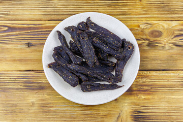 Slices of biltong (South African dried meat) on wooden table. Top view