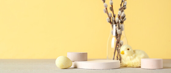 Empty podiums with Easter egg, willow branches and chicken on yellow background with space for text © Pixel-Shot