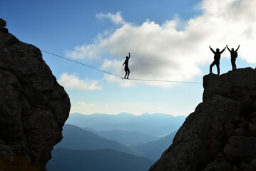 walking on a tightrope and a successful team in the mountains