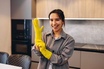 young happy cleaning woman putting on rubber gloves