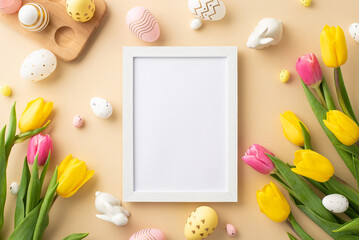 Naklejka na ściany i meble Easter concept. Top view photo of photo frame colorful easter eggs ceramic bunnies yellow and pink tulips and wooden egg holder on isolated pastel beige background with empty space