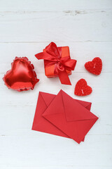 Composition with beautiful candles, envelopes, gift box and balloon on light wooden background. Valentine's Day celebration