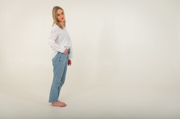 Portrait of a young, emotional, happy girl without makeup, smiling at the camera, gesturing with her hands, standing on a white background. Place for writing