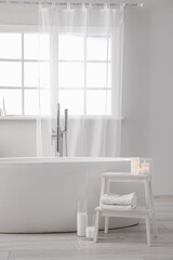 Modern bathtub and table with candles in bathroom interior