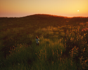 Fototapeta na wymiar Child in rolling countryside during sunset. Generative AI.