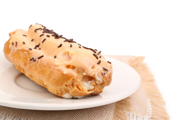 Plate with sweet eclair and napkin isolated on white background