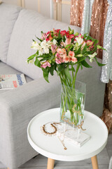 Vase with alstroemeria flowers and jewelry on table in dressing room