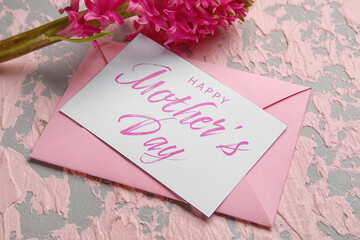Card with text HAPPY MOTHER'S DAY, envelope and beautiful hyacinth flower on grunge background, closeup