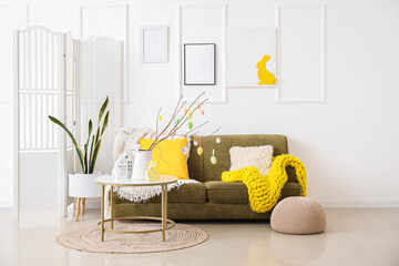Interior of light living room with Easter decor, green sofa and table