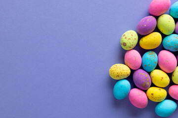 Image of multi coloured chocolate easter eggs with copy space on purple background - Powered by Adobe