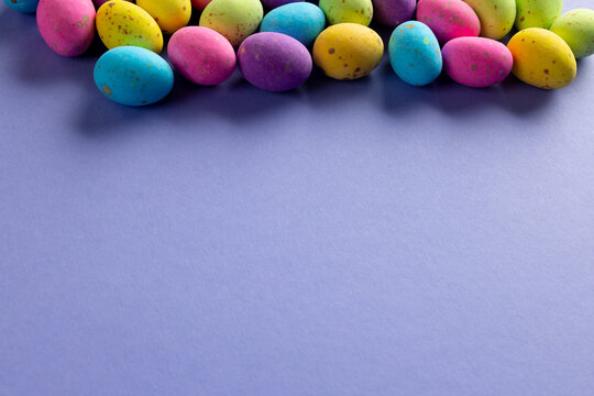 Image of multi coloured easter eggs with copy space on purple background