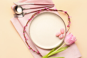 Table setting with Easter eggs, tulip flowers and cutlery on beige background