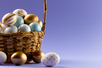 Fototapeta premium Image of multi coloured easter eggs in basket and copy space on purple background